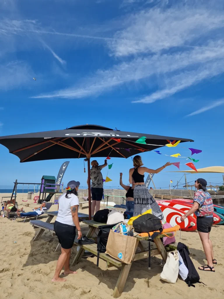 People hanging up flags on a parasol at the beach