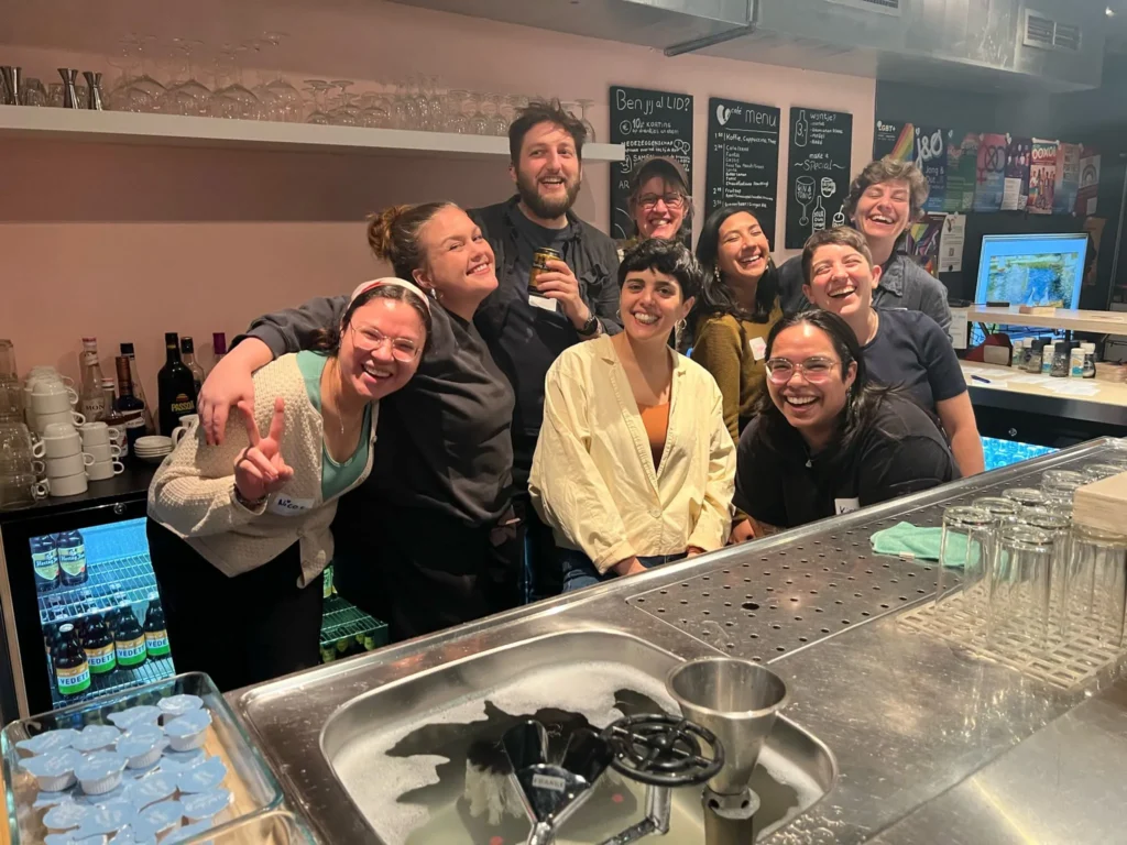 A group of QP volunteers standing behind the bar, smiling